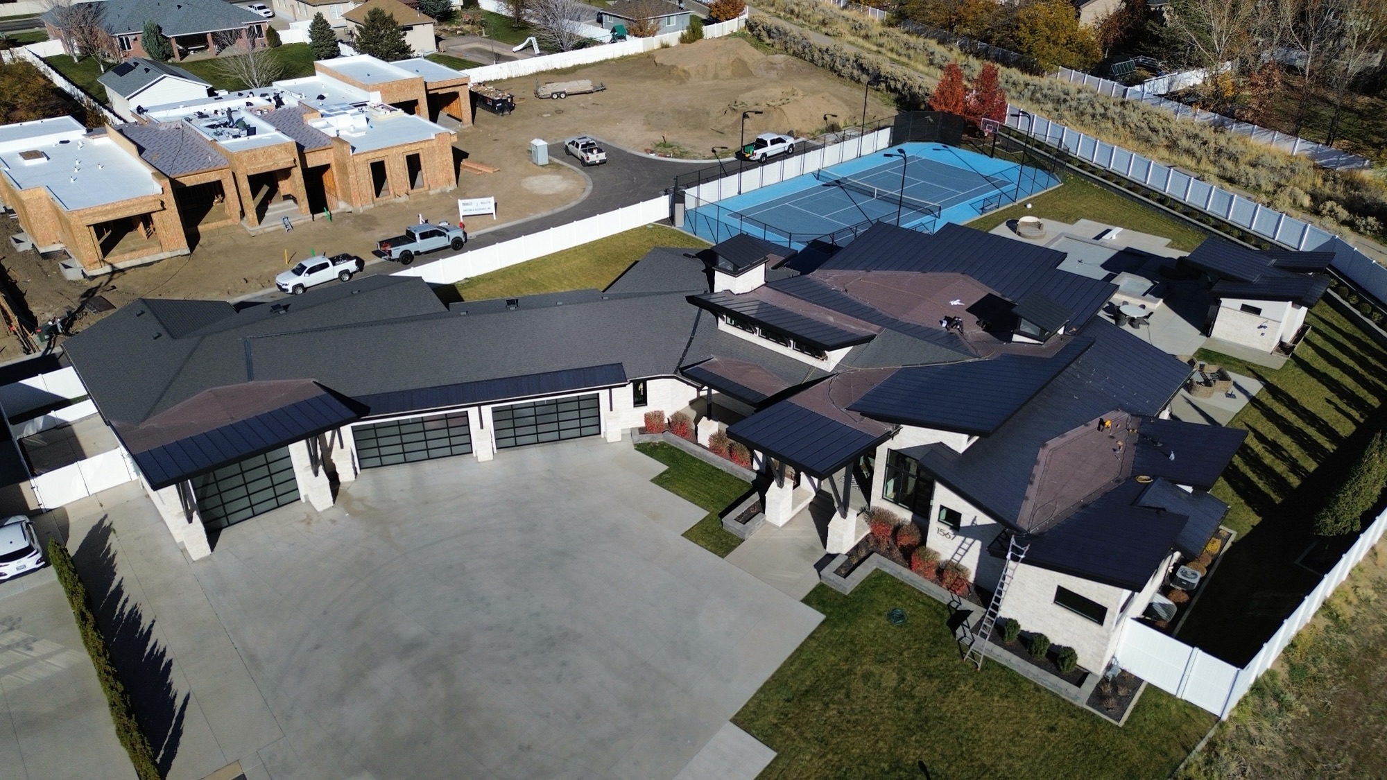 Aerial view of a large luxury home with a new dark architectural shingle roof