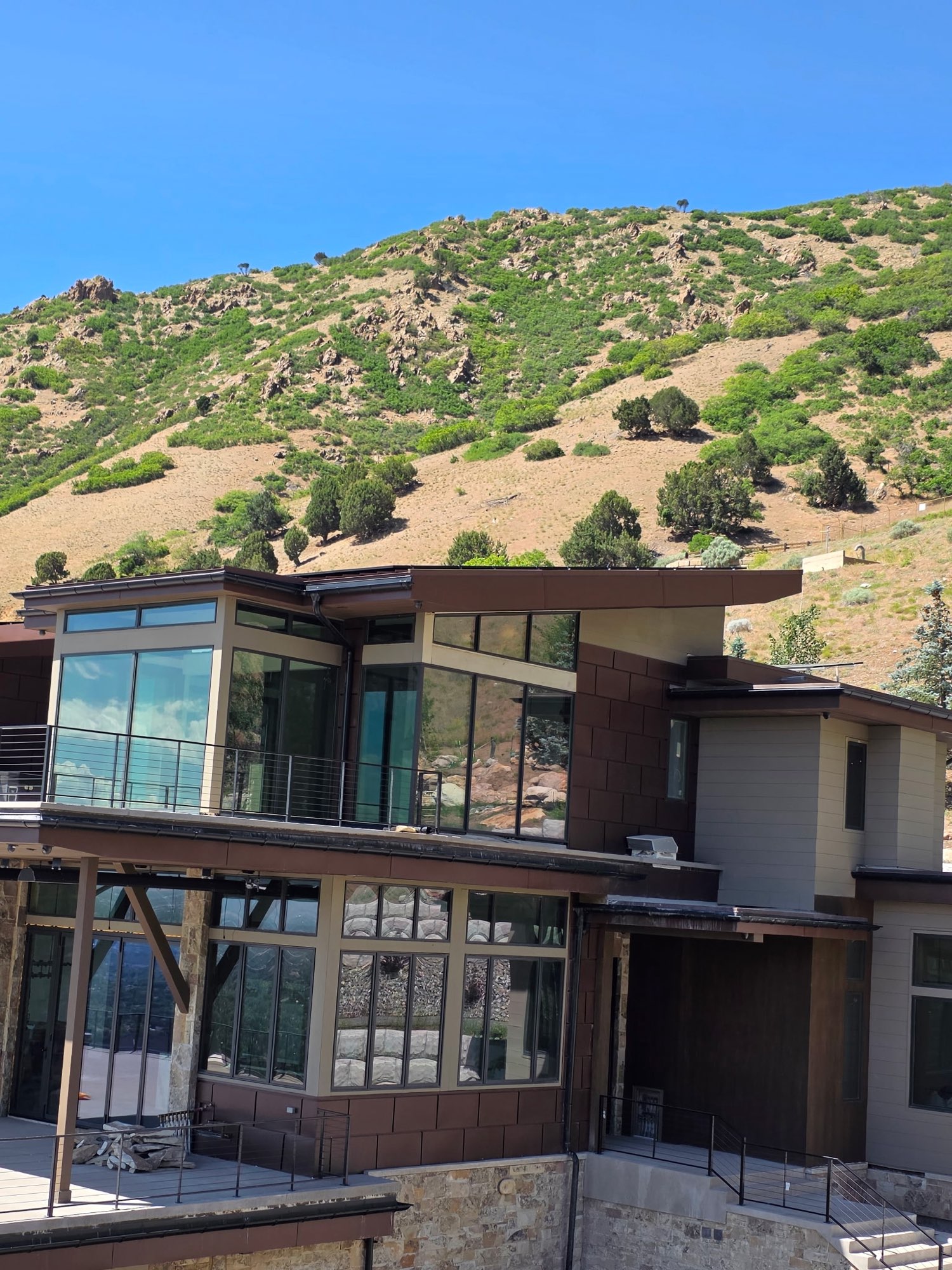 Mountain modern home with bronze metal panel siding and flat roof overhangs in the Utah foothills
