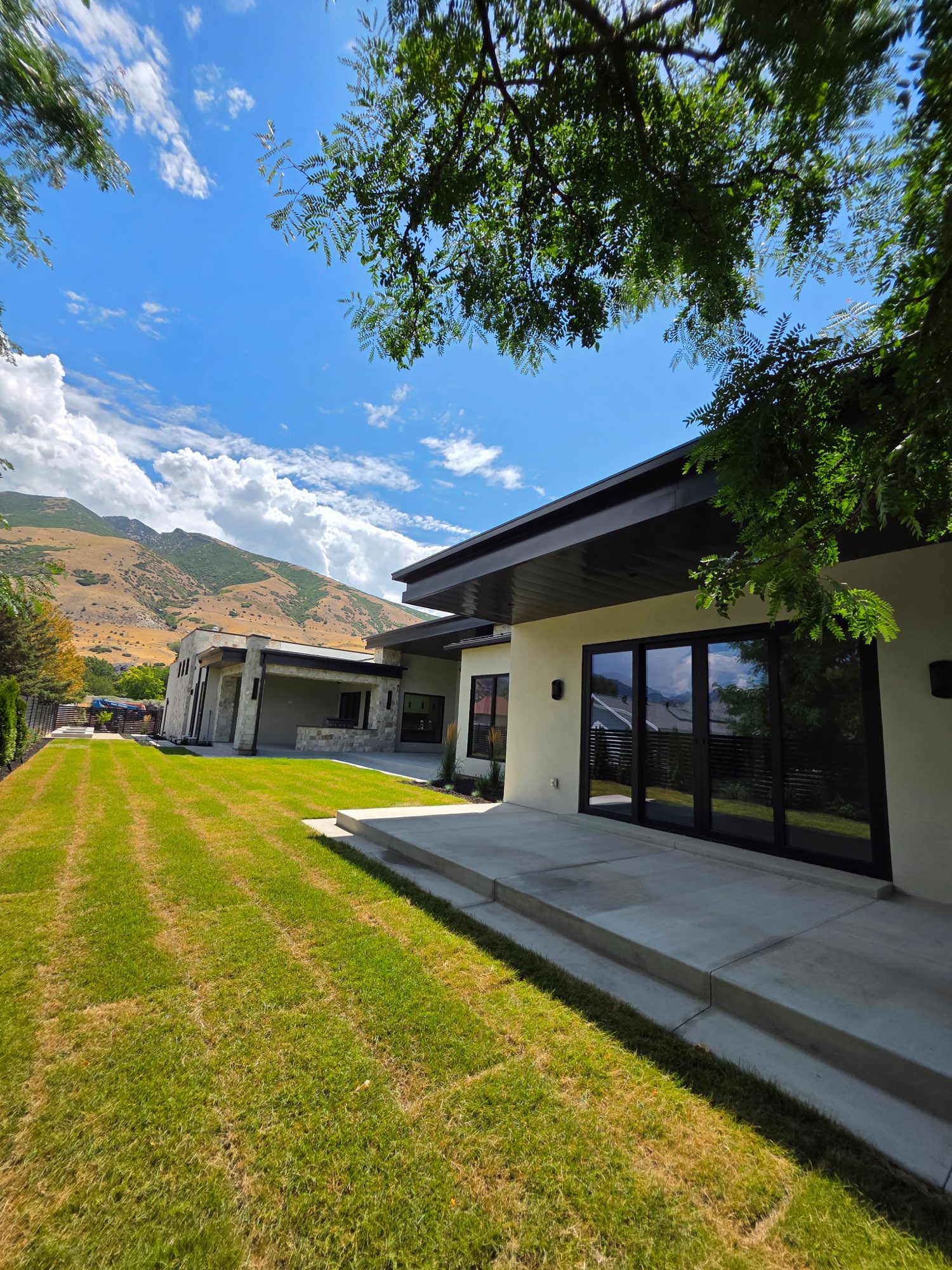 Modern Utah home with a deep dark soffit, fascia and low-slope roofline against the mountains